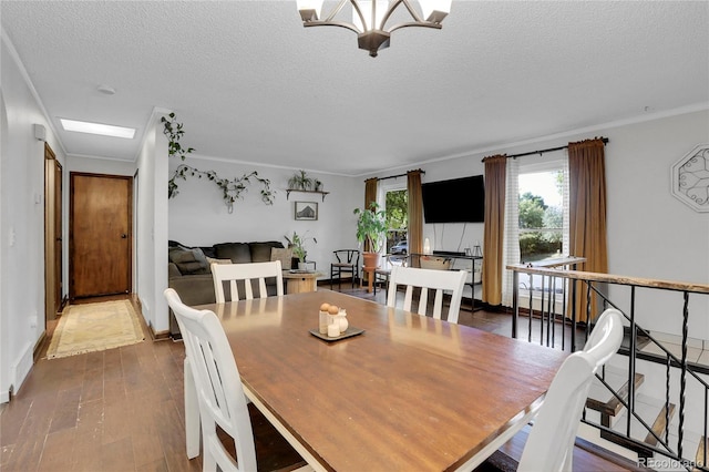 dining space with baseboards, ornamental molding, wood finished floors, a textured ceiling, and a chandelier