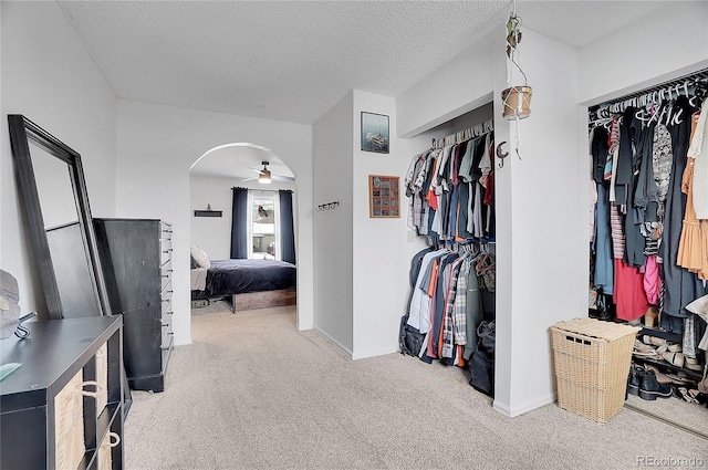 walk in closet featuring arched walkways, ceiling fan, and carpet