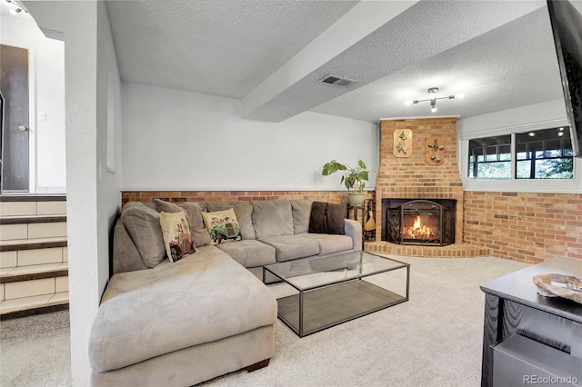 carpeted living room with a brick fireplace, brick wall, visible vents, and a textured ceiling