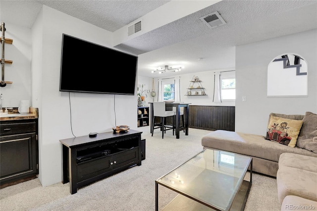 living room featuring light colored carpet, visible vents, and a textured ceiling