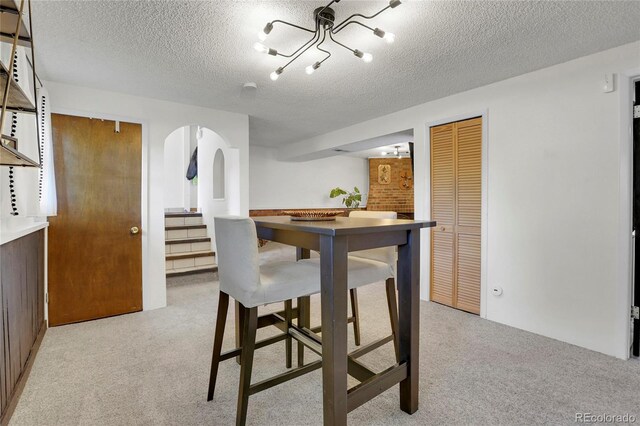 dining room with light carpet, stairway, a textured ceiling, and arched walkways