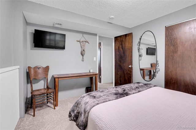 bedroom with visible vents, light colored carpet, and a textured ceiling