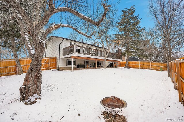 snow covered back of property featuring a fire pit and a fenced backyard