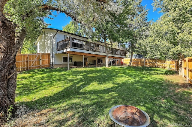 back of property featuring a yard, an outdoor fire pit, a fenced backyard, and a wooden deck