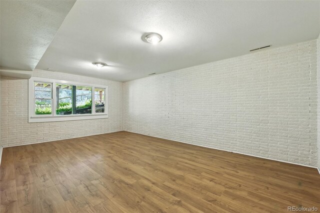 1037 Wagonwheel Gap Rd, Boulder, CO 80302 - empty room featuring wood finished floors, brick wall, and a textured ceiling