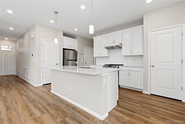 27639 E 7th Ln, Aurora, CO 80018 - kitchen featuring freestanding refrigerator, a sink, under cabinet range hood, wood finished floors, and white cabinetry
