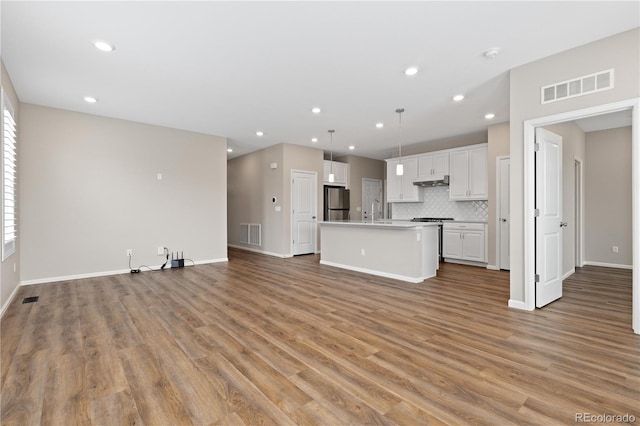 27639 E 7th Ln, Aurora, CO 80018 - unfurnished living room featuring light wood-type flooring, baseboards, recessed lighting, and a sink