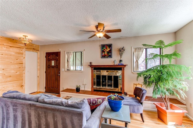 1275 Niagara St, Denver, CO 80220 - living room with a ceiling fan, healthy amount of natural light, wood finished floors, a textured ceiling, and a stone fireplace