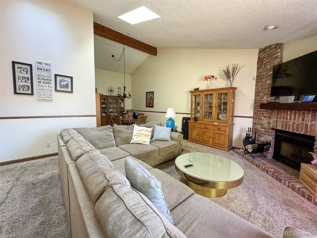 living area featuring carpet, a fireplace, a chandelier, a textured ceiling, and baseboards
