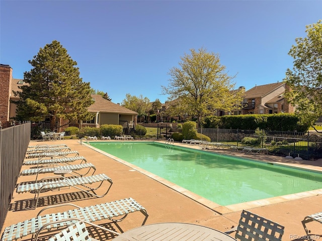 community pool with fence and a patio area