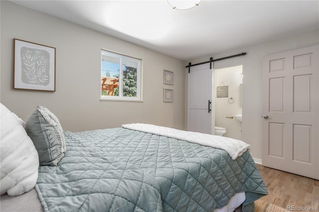 1120 Hartford Dr, Boulder, CO 80305 - bedroom with a barn door, wood finished floors, and ensuite bath