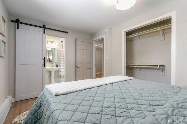 1120 Hartford Dr, Boulder, CO 80305 - bedroom with a barn door, wood finished floors, a closet, and ensuite bath