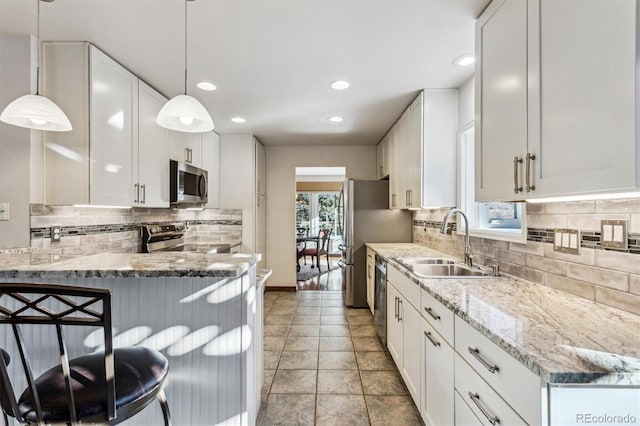 kitchen with sink, decorative light fixtures, stainless steel appliances, light stone countertops, and white cabinets