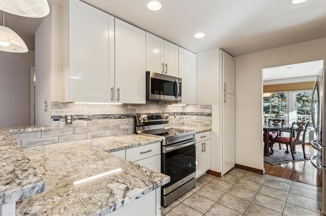 kitchen with appliances with stainless steel finishes, pendant lighting, white cabinets, decorative backsplash, and light stone counters