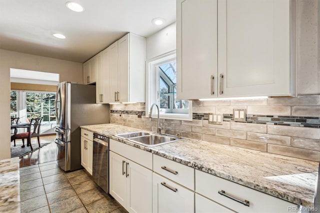 kitchen featuring stainless steel appliances, white cabinetry, plenty of natural light, and sink