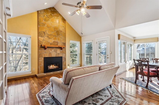 living room with a stone fireplace, a wealth of natural light, and light hardwood / wood-style floors