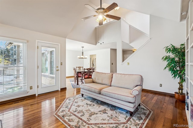 living room with dark wood-type flooring, high vaulted ceiling, and ceiling fan with notable chandelier