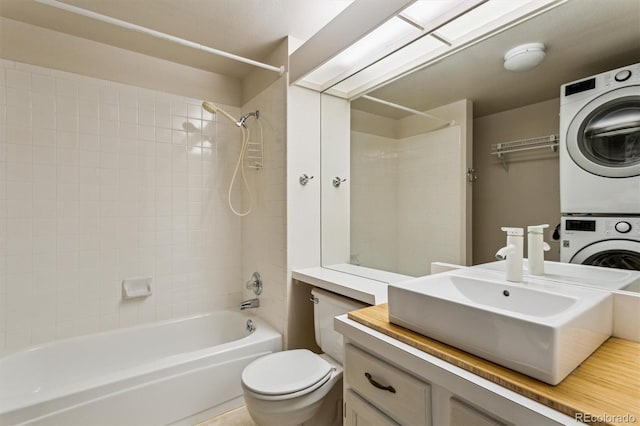 full bathroom with stacked washer and dryer, vanity, tiled shower / bath combo, and toilet