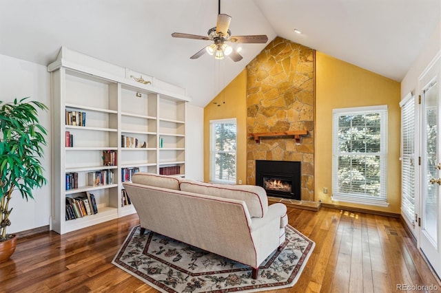 living room with dark wood-type flooring, ceiling fan, a fireplace, and high vaulted ceiling