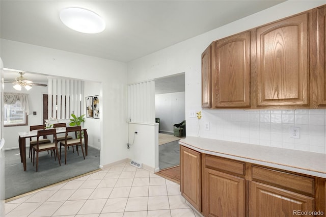 kitchen featuring ceiling fan, light tile patterned floors, and backsplash