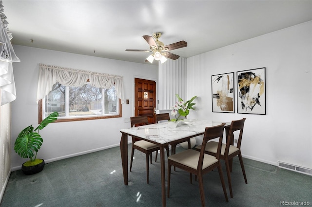 dining space featuring ceiling fan and dark colored carpet