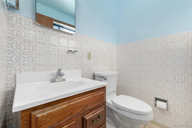 bathroom featuring vanity, tile walls, and toilet