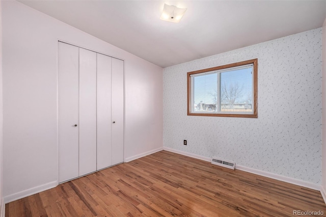 unfurnished bedroom featuring hardwood / wood-style floors and a closet