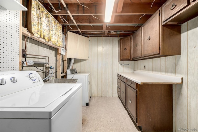 washroom with cabinets, washer and dryer, and wood walls