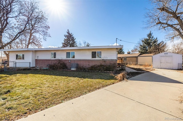 ranch-style home featuring a front yard and a storage unit