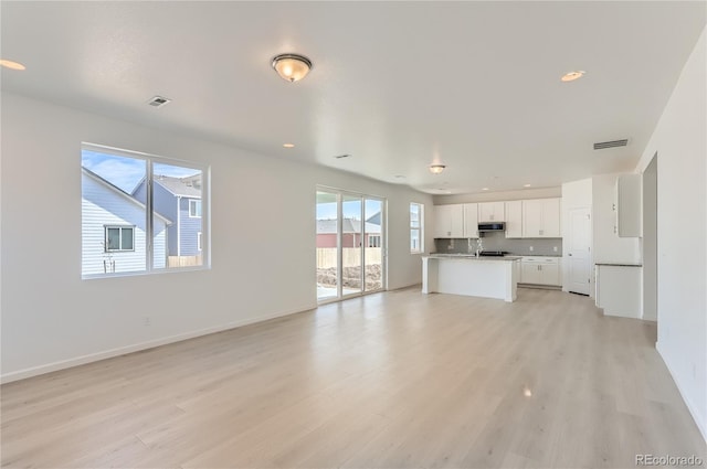 unfurnished living room with recessed lighting, visible vents, baseboards, and light wood finished floors