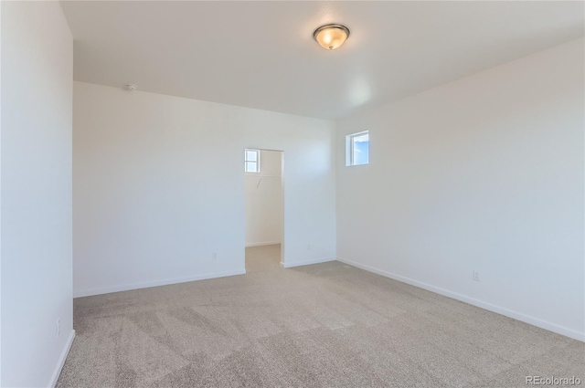 unfurnished room featuring baseboards and light carpet