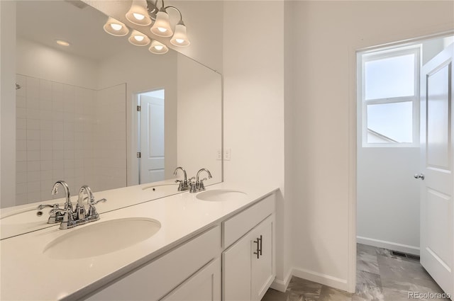 bathroom with double vanity, baseboards, marble finish floor, and a sink