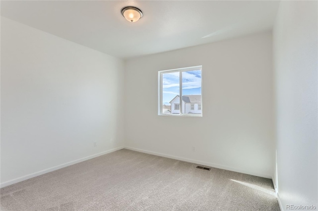 spare room featuring visible vents, light colored carpet, and baseboards