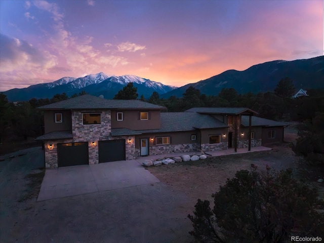 17158 County Road 363, Buena Vista, CO 81211 - view of front facade with stone siding, driveway, a mountain view, an attached garage, and stucco siding