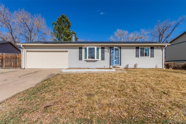 single story home featuring an attached garage, fence, a front yard, roof mounted solar panels, and driveway