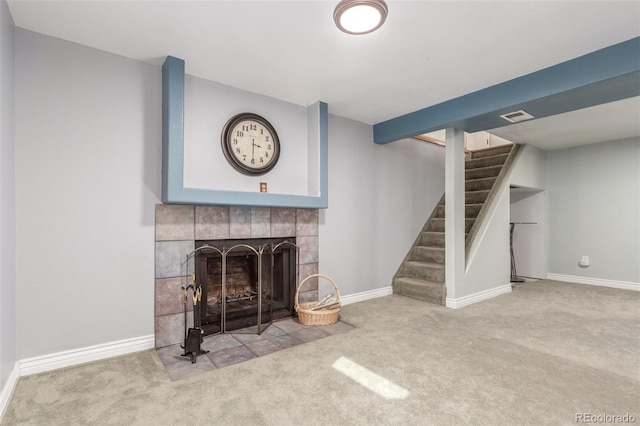 unfurnished living room with carpet, baseboards, visible vents, a tile fireplace, and stairs