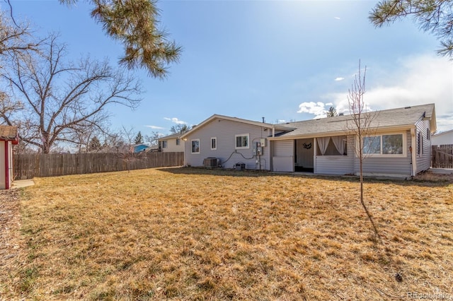 back of house featuring central AC unit, a yard, and fence