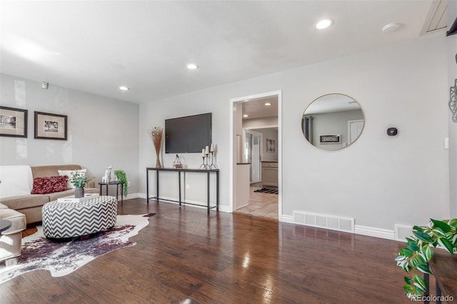 living area with recessed lighting, wood finished floors, visible vents, and baseboards