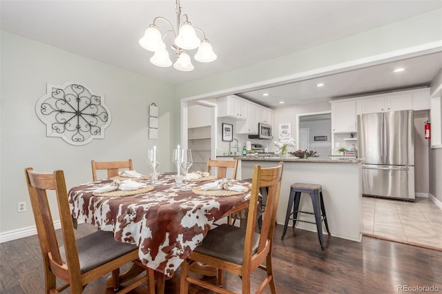 dining space featuring a chandelier, recessed lighting, baseboards, and wood finished floors