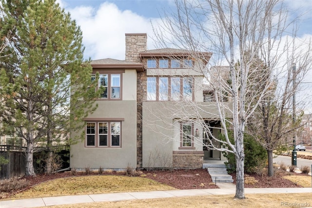 view of front facade with a chimney, fence, and stucco siding