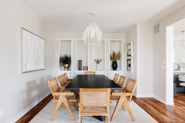 dining space featuring an inviting chandelier, baseboards, visible vents, and wood finished floors