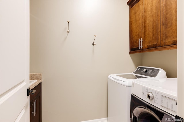 clothes washing area featuring independent washer and dryer and cabinet space