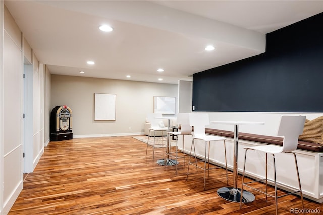 bar featuring baseboards, light wood finished floors, and recessed lighting