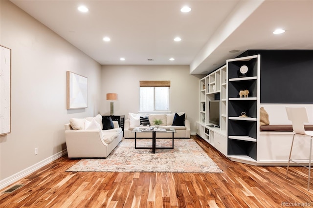 living area with baseboards, wood finished floors, visible vents, and recessed lighting