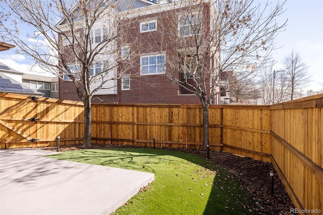 view of yard with a patio, a fenced backyard, and a gate