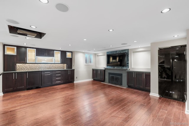 172 S Forest St, Denver, CO 80246 - kitchen with black fridge, wood finished floors, decorative backsplash, a fireplace, and glass insert cabinets