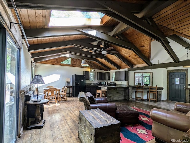 living room featuring ceiling fan, light hardwood / wood-style flooring, lofted ceiling with skylight, and wooden ceiling