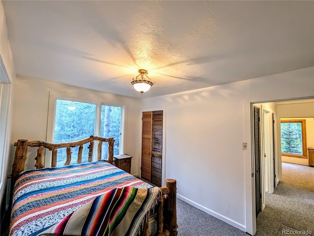 bedroom with a closet, dark carpet, and a textured ceiling