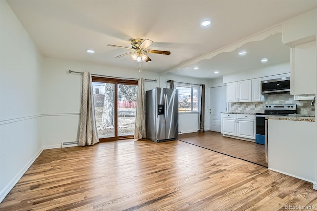 kitchen featuring tasteful backsplash, white cabinets, ceiling fan, stainless steel appliances, and light hardwood / wood-style flooring