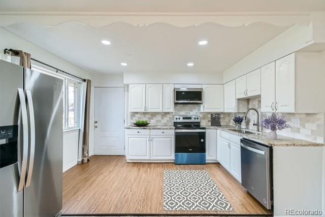 kitchen featuring stainless steel appliances, light wood-style floors, white cabinetry, and a sink